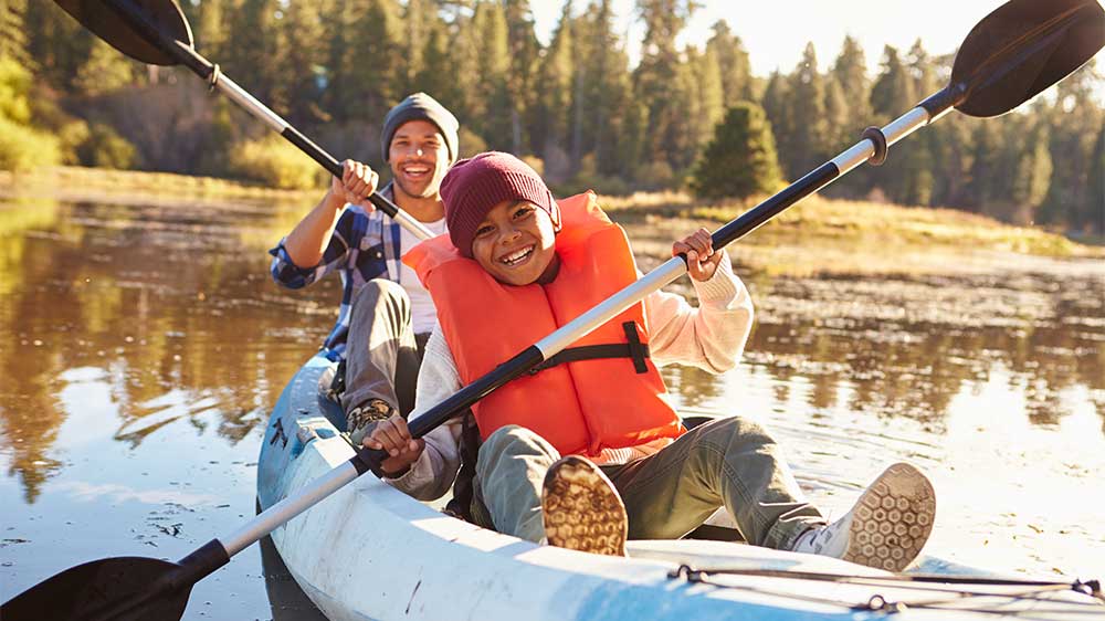 dad and son smiling while canoeing