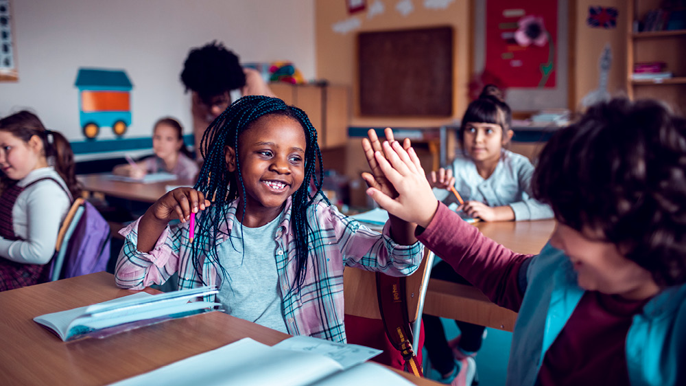 young students high fiving in classroom