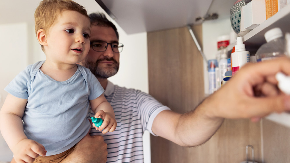 Caucasian Father And His Baby Son Taking Medicines Out Of The Medicine Cabinet