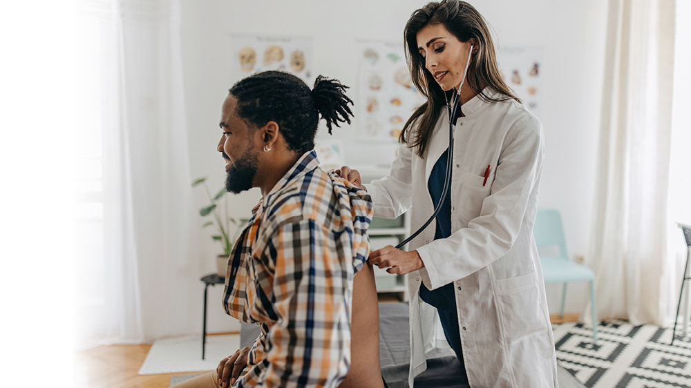 doctor listening to man's lungs with stethoscope