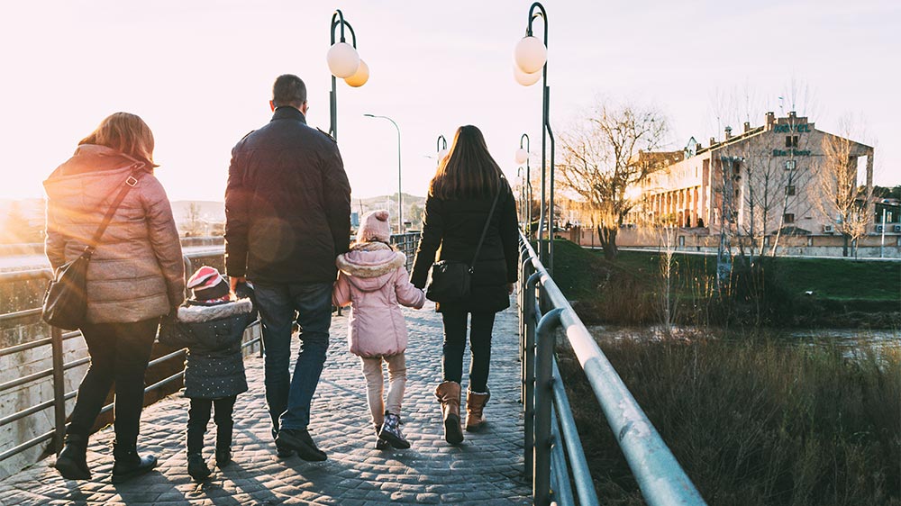 three adults and two children walking over a wintery bridge