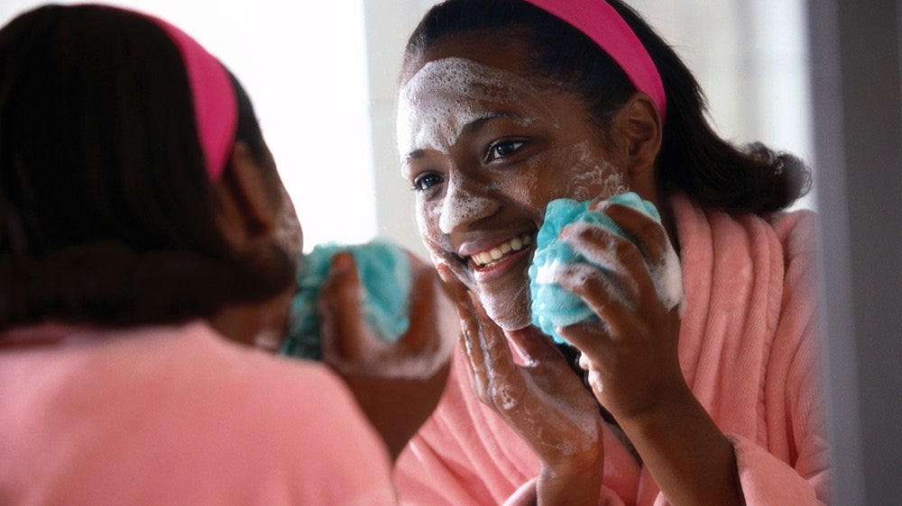 Woman washing her face in brightly lit bathroom