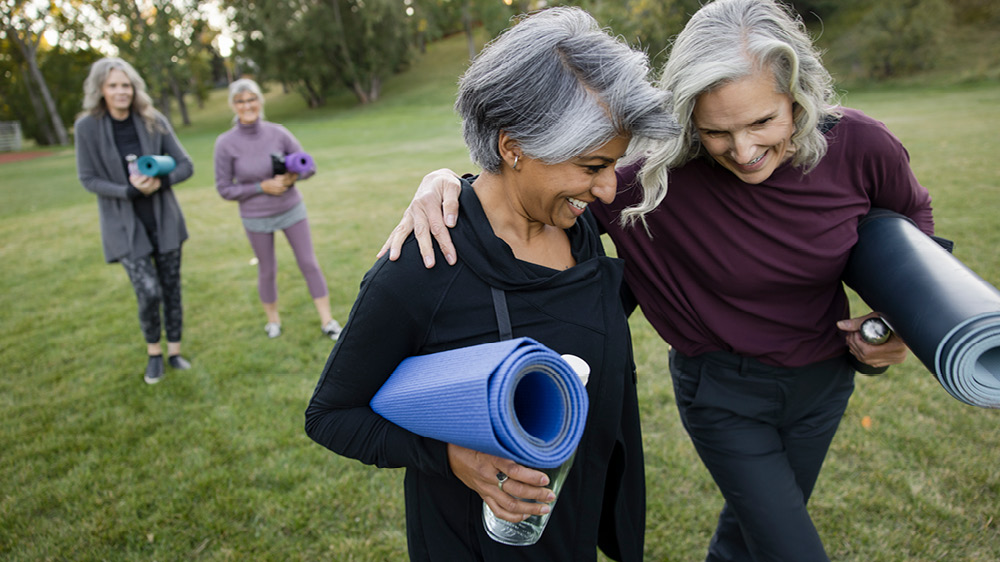 group of older women in park with yoga mats