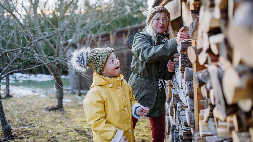 child with down syndrome and mother in winter getting chopped wood