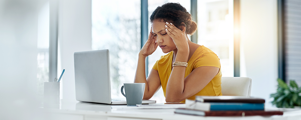 Woman at computer fighting a headache.