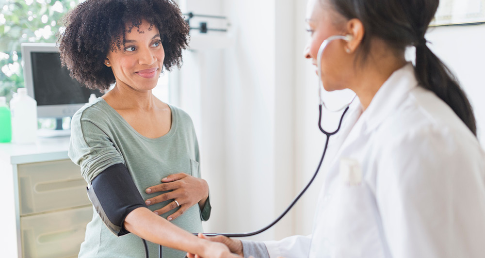 pregnant woman getting her blood pressure taken by doctor