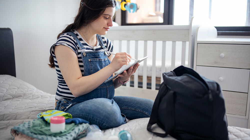 pregnant woman packing her hospital bag with pump, clothes and towels