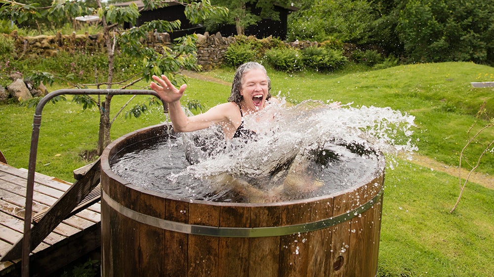 older woman splashing in cold outdoor tub