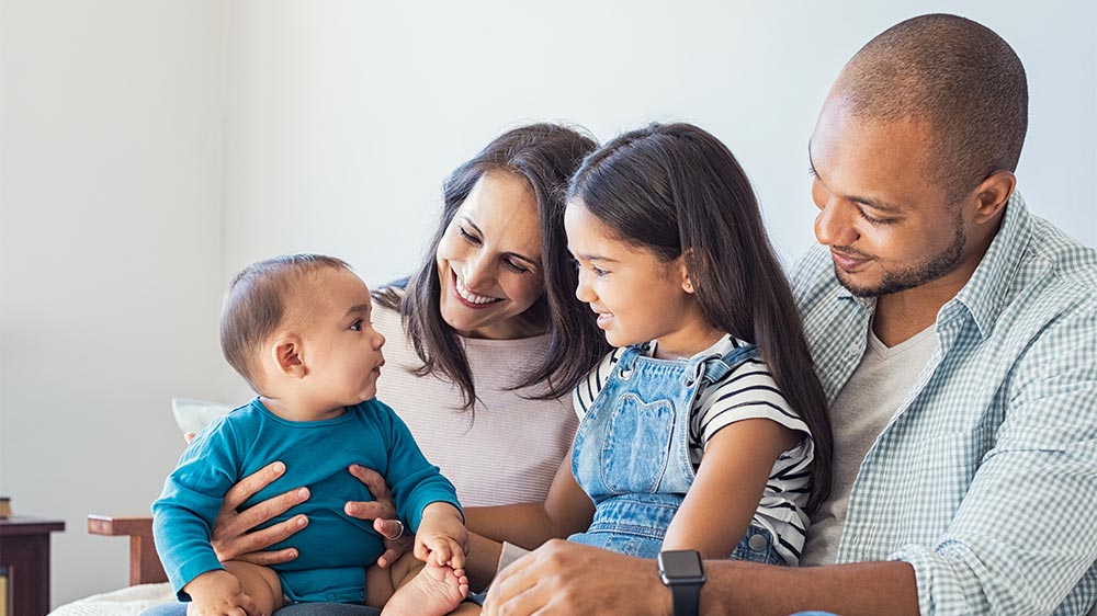 two parents holding their newborn and toddler