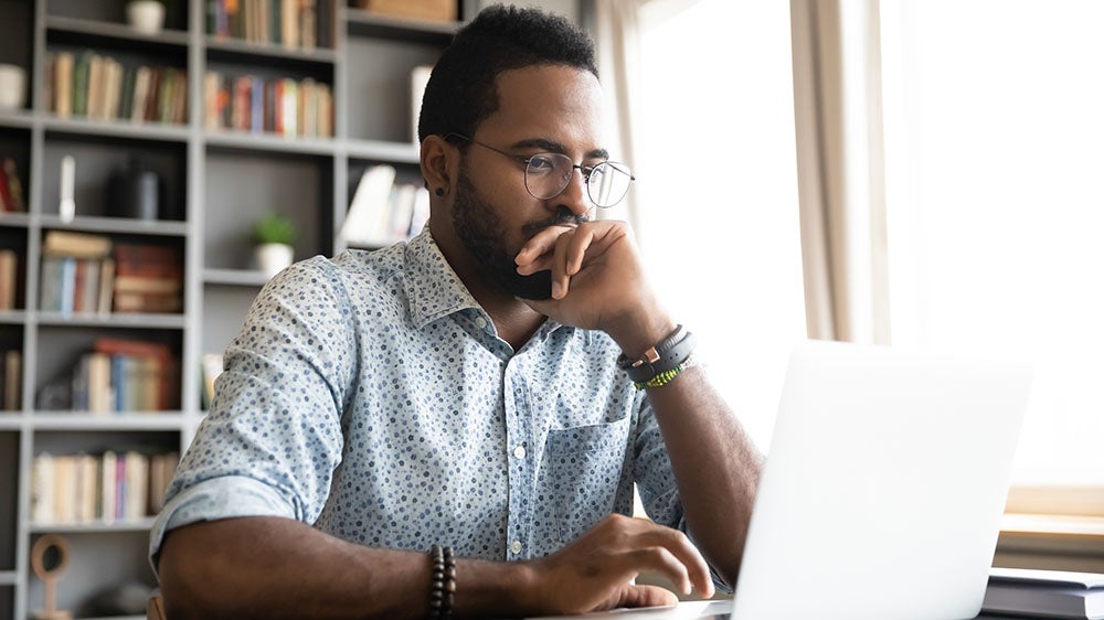 man sitting at a desk on his laptop