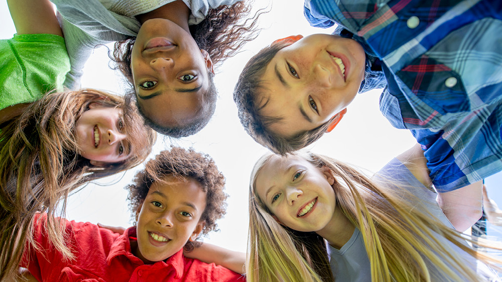 Children in circle with their arms around one another 