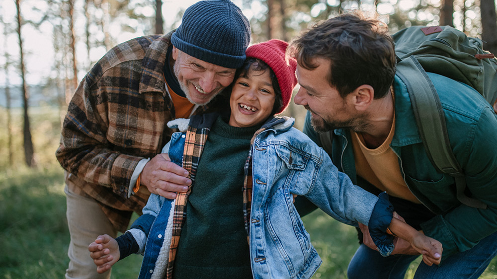 grandfather and father cuddling young son on hike