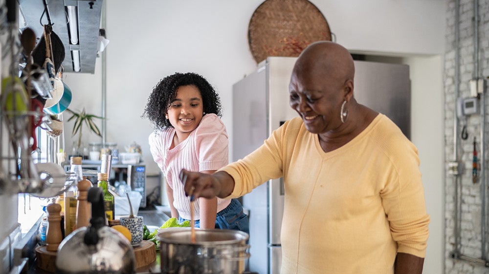 Woman cooking dinner with young child 