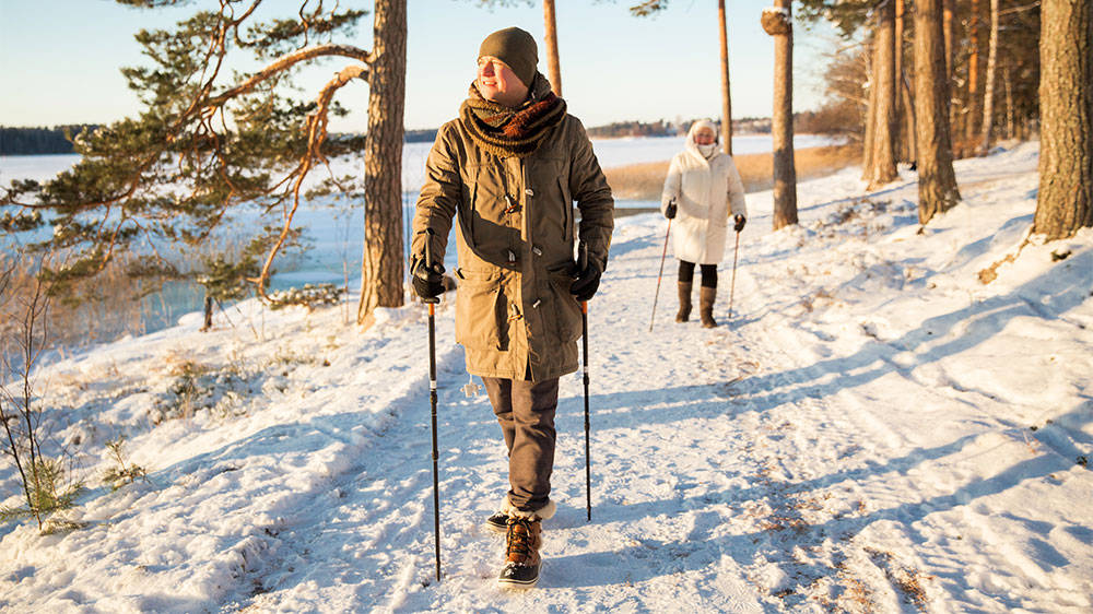 two women on snowy path with walking poles 