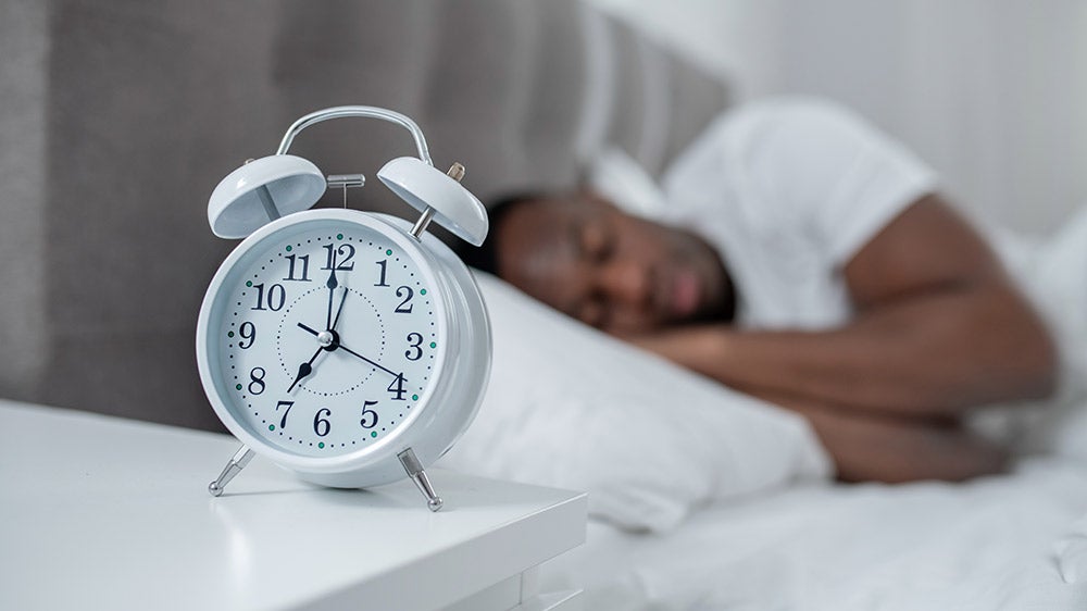 man sleeping peacefully with alarm clock