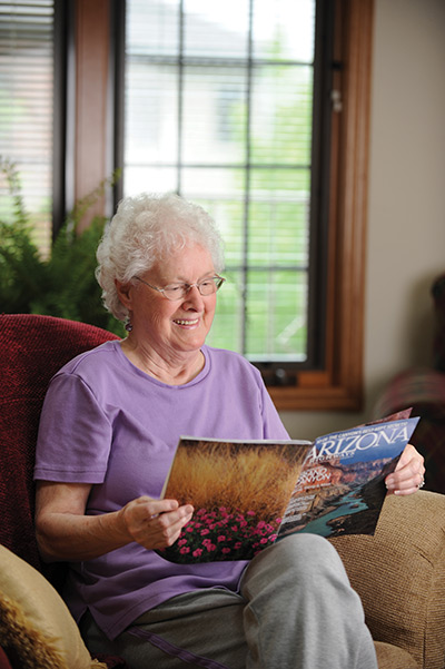 Tenant reading in community living room at Ellen Kennedy Living Center