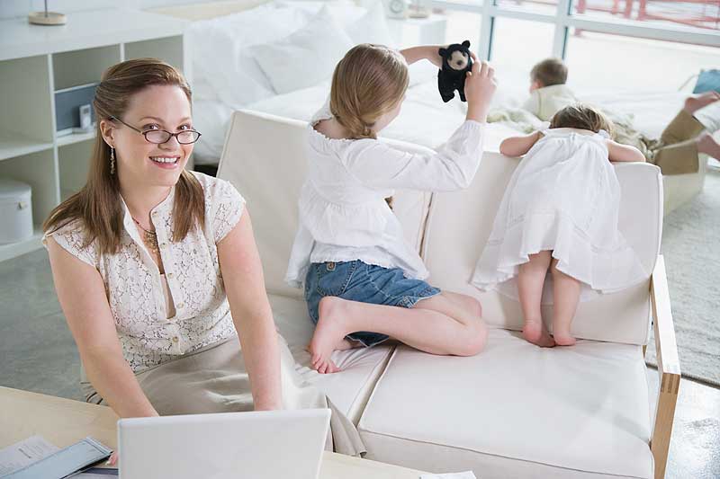 Mother working on the computer while children play