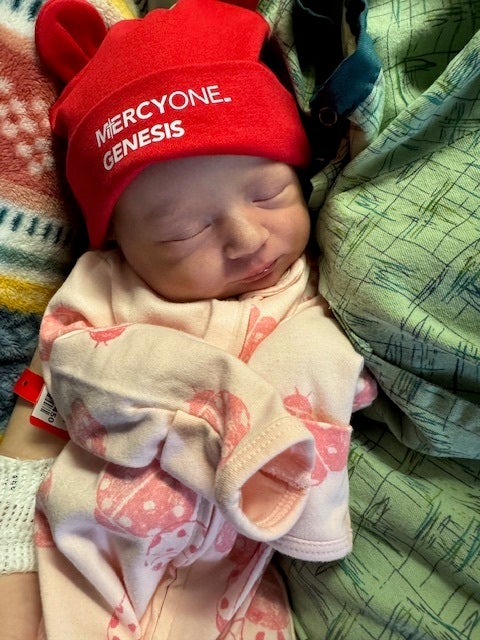 Image of a newborn wearing a red MercyOne Genesis hat.