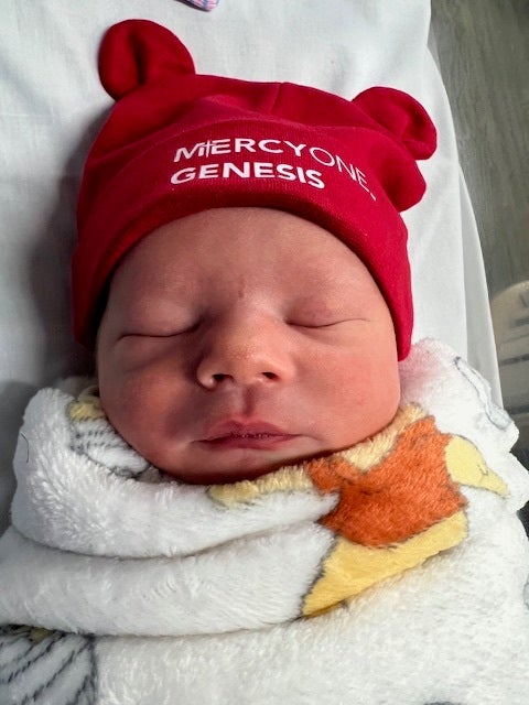 Image of a newborn wearing a red MercyOne Genesis hat.