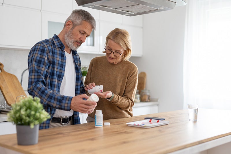 Two adults examining OTC pain reliever bottle